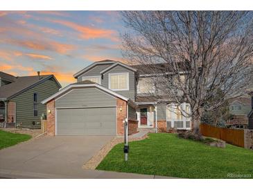 Charming two-story home with a well-manicured lawn, attached garage, and delightful curb appeal, set against a colorful sunset at 10900 Parker Vista Rd, Parker, CO 80138