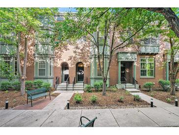 Brick townhouse exterior with front yard landscaping and trees providing shade at 8735 E 29Th Pl, Denver, CO 80238