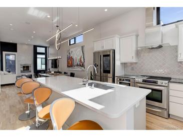 Bright, modern kitchen features stainless steel appliances, white cabinets, and a large center island with seating at 2442 Champa St, Denver, CO 80205