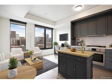 Bright, modern living room with large windows offering stunning city views, an island, and sleek, gray kitchen cabinets at 1750 Wewatta St # 1536, Denver, CO 80202