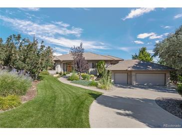 Beautiful single-story home featuring manicured landscaping, lush lawn and a three car garage at 10985 Ambush Rock, Littleton, CO 80125