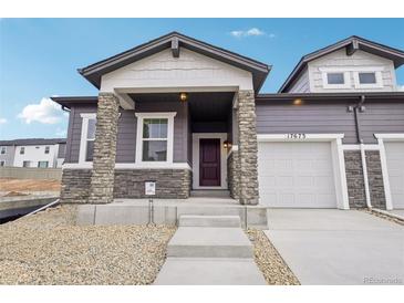 Inviting front entrance with stone accents, gray siding, and a well-maintained landscaped approach to the front door at 17673 Brass Buckle Way, Monument, CO 80132