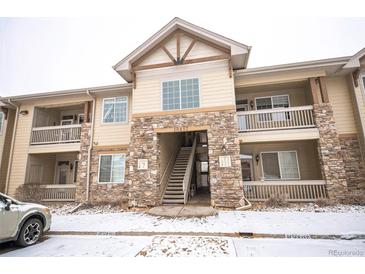 Exterior of the building with stone accents, multiple floors, and balconies covered in light snow at 10487 W Hampden Ave # 101, Lakewood, CO 80227