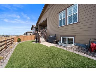 Landscaped backyard featuring artificial turf, a wooden fence, and stairs leading to the home's entrance at 4475 Hidden Gulch Rd, Castle Rock, CO 80104
