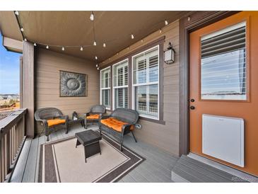 Inviting porch with wicker furniture, string lights, and an orange front door at 4475 Hidden Gulch Rd, Castle Rock, CO 80104