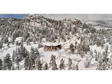 Stunning mountain home nestled amongst snow-covered trees with an amazing view of the surrounding landscape at 3999 Evans Ranch Rd, Evergreen, CO 80439