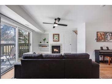 Comfortable living room with a fireplace, balcony access, and light hardwood floors at 6435 S Dayton St # 103, Englewood, CO 80111