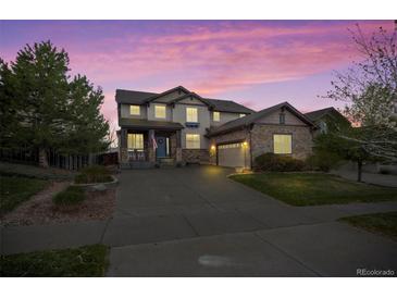 Beautiful two-story home with stone accents, attached garage, and a well-manicured front yard at dusk at 6475 S Newcastle Way, Aurora, CO 80016