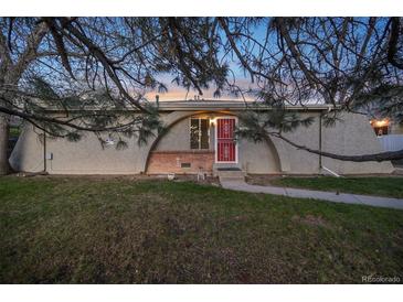 Unique home exterior with a red security door and arch design elements surrounded by mature trees and green lawn at 1280 Sable Blvd, Aurora, CO 80011