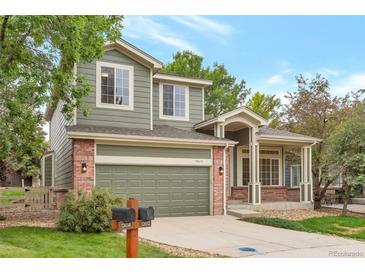 Charming two-story home with a well-maintained lawn, complemented by a brick facade and a covered front porch at 13612 Plaster Cir, Broomfield, CO 80023