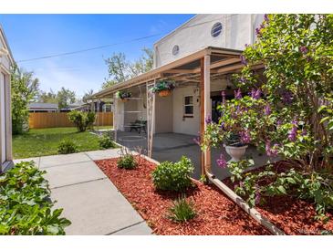 Inviting covered back patio with wrought iron posts and flowering plants at 1400 S Knox Ct, Denver, CO 80219
