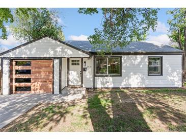 Charming renovated home with a modern wood-paneled garage door and manicured lawn at 2430 Eaton St, Edgewater, CO 80214