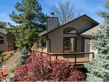 Beautiful home featuring a charming deck, lush landscaping, mature trees and architectural details at 837 Meadow Run, Golden, CO 80403