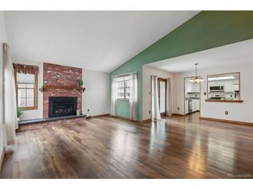 Bright living room with a beautiful fireplace, hardwood floors, and a large window at 2838 S Heather Gardens Way # A, Aurora, CO 80014