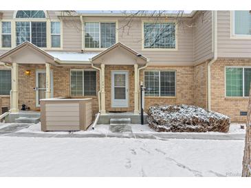 Charming townhome featuring a brick facade and covered entryway during the winter season at 1129 W 112Th Ave # C, Denver, CO 80234