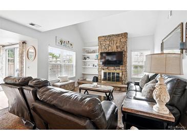 Inviting living room features a stone fireplace, vaulted ceilings, and abundant natural light at 13228 E Asbury Dr, Aurora, CO 80014