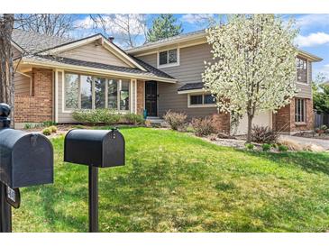 Charming two-story home featuring a well-manicured front yard and a mix of brick and siding exterior, with a blooming tree at 4626 E Links Dr, Centennial, CO 80122