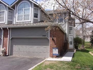 Charming townhouse featuring a two-car garage, brick accents, and well-maintained landscaping at 7707 S Monaco Cir, Centennial, CO 80112