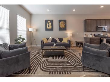 Well-lit living room featuring a comfortable seating arrangement and an open flow to the kitchen at 10177 E 62Nd Ave, Denver, CO 80238