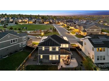 Stunning aerial view of home with solar panels, patio, fenced yard, and neighborhood park at 12264 Olive Way, Thornton, CO 80602