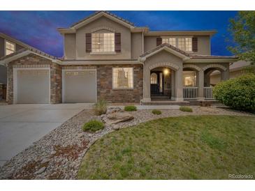 Charming two-story home featuring a stone facade and a well-manicured front yard and three-car garage at 1385 Candleglow St, Castle Rock, CO 80109