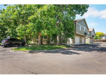 A view of the townhouse, with mature trees, and a car parked in front at 1155 S Fairplay Cir # D, Aurora, CO 80012