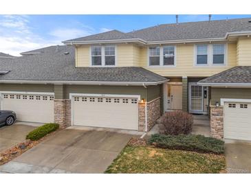 Inviting exterior view of a two-story townhome with a two-car garage and stone accents at 3000 E 112Th Ave # 102, Northglenn, CO 80233