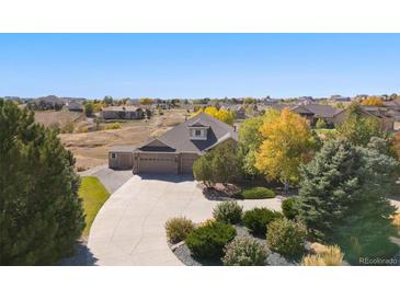 An elevated view of a home featuring mature landscaping, a three-car garage, and a circular driveway at 10044 E 146Th Pl, Brighton, CO 80602