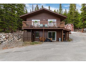 Charming two-story cabin with a large deck surrounded by lush greenery and a red barn at 159 Lake Rd, Idaho Springs, CO 80452