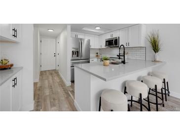 Bright kitchen boasts white cabinets, modern countertops, and stainless steel appliances at 8799 Independence Way, Arvada, CO 80005