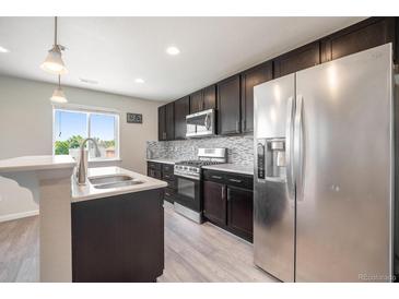 Well-equipped kitchen with stainless steel appliances, dark cabinets, and a bright window over the sink at 1732 Aspen Meadows Cir, Federal Heights, CO 80260