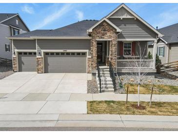 Charming single-Gathering home with a covered porch, stone accents, and a three-car garage at 10987 Ouray St, Commerce City, CO 80022