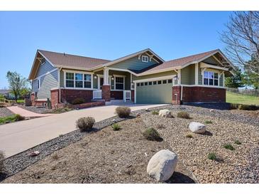 Charming green home featuring a well-manicured front yard and a red brick facade with a two-car garage at 23312 E Chestnut Pl, Aurora, CO 80016