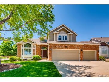 Brick two-story house with a three-car garage and manicured lawn at 10141 Brady Pl, Highlands Ranch, CO 80130