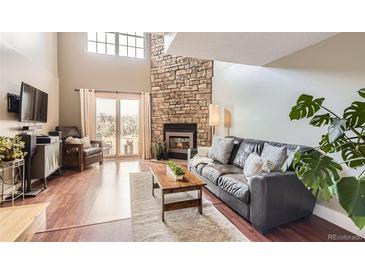 Bright living room featuring a stone fireplace, hardwood floors, and sliding glass doors at 9747 W Cornell Pl, Lakewood, CO 80227