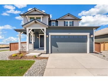 Two-story home with blue siding, a gray garage door, front porch, and professionally landscaped front yard at 2237 Garden Ave, Brighton, CO 80601
