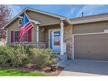 Charming home with a tidy front yard, American flag, and inviting brick accents at 11462 Iola St, Commerce City, CO 80640