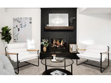 Cozy living room with a black brick fireplace, wooden mantel, and stylish armchairs at 7307 S Birch St, Centennial, CO 80122