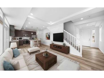 Bright open-concept living room features recessed lighting, a modern staircase and stylish decor, seamlessly connecting to the kitchen at 1170 Sugarloaf Ln, Erie, CO 80516