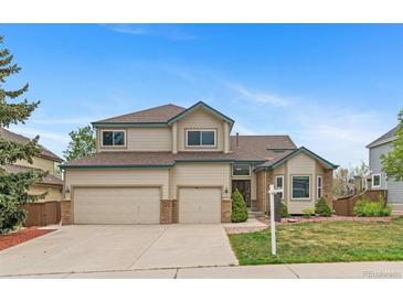 Charming two-story home with three-car garage and manicured front yard landscaping on a sunny day at 9983 Cottoncreek Dr, Highlands Ranch, CO 80130