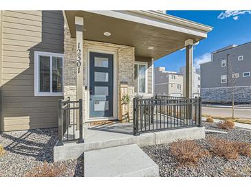 Charming front porch with black railings and a modern front door welcomes you home at 12301 Festival Ln, Thornton, CO 80241