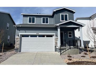 Charming two-story home featuring a two-car garage, a cozy front porch, and stylish gray siding at 2221 Flower Blossom Ave, Brighton, CO 80601
