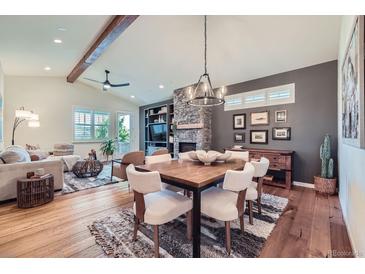 Inviting living room with a stone fireplace, wood floors, and a cozy dining area with modern chandelier at 7201 W Asbury Pl, Lakewood, CO 80227