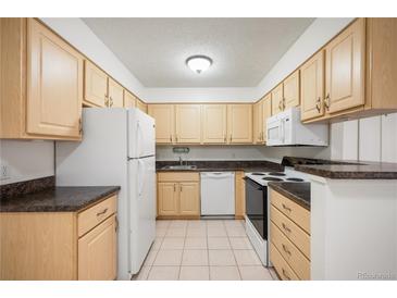 Bright kitchen featuring light wood cabinets, white appliances, and tile flooring at 3335 S Ammons St # 6-102, Lakewood, CO 80227