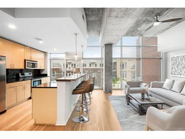 Open concept living area with hardwood floors, island with bar seating, and floor to ceiling windows at 1700 Bassett St # 703, Denver, CO 80202