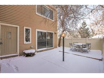 Snow covered backyard with patio furniture and a wood fence at 9573 E Kansas Cir # 57, Denver, CO 80247