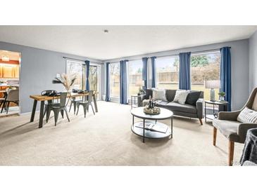 Bright living room with large windows, blue curtains, and modern furnishings; neutral tones create a cozy atmosphere at 10050 W 8Th Pl, Lakewood, CO 80215