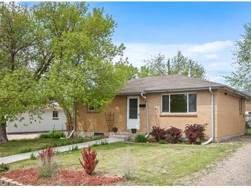 Well-kept brick home with a lush front yard, mature trees, and a welcoming pathway at 7987 Durango St, Denver, CO 80221