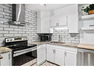 Updated kitchen featuring granite countertops, white cabinets, and stainless steel appliances at 705 S Alton Way # 6B, Denver, CO 80247