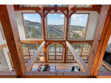 Bright living room features vaulted ceilings, wood beams, hardwood floors and expansive windows with mountain views at 13326 Kuehster Rd, Littleton, CO 80127